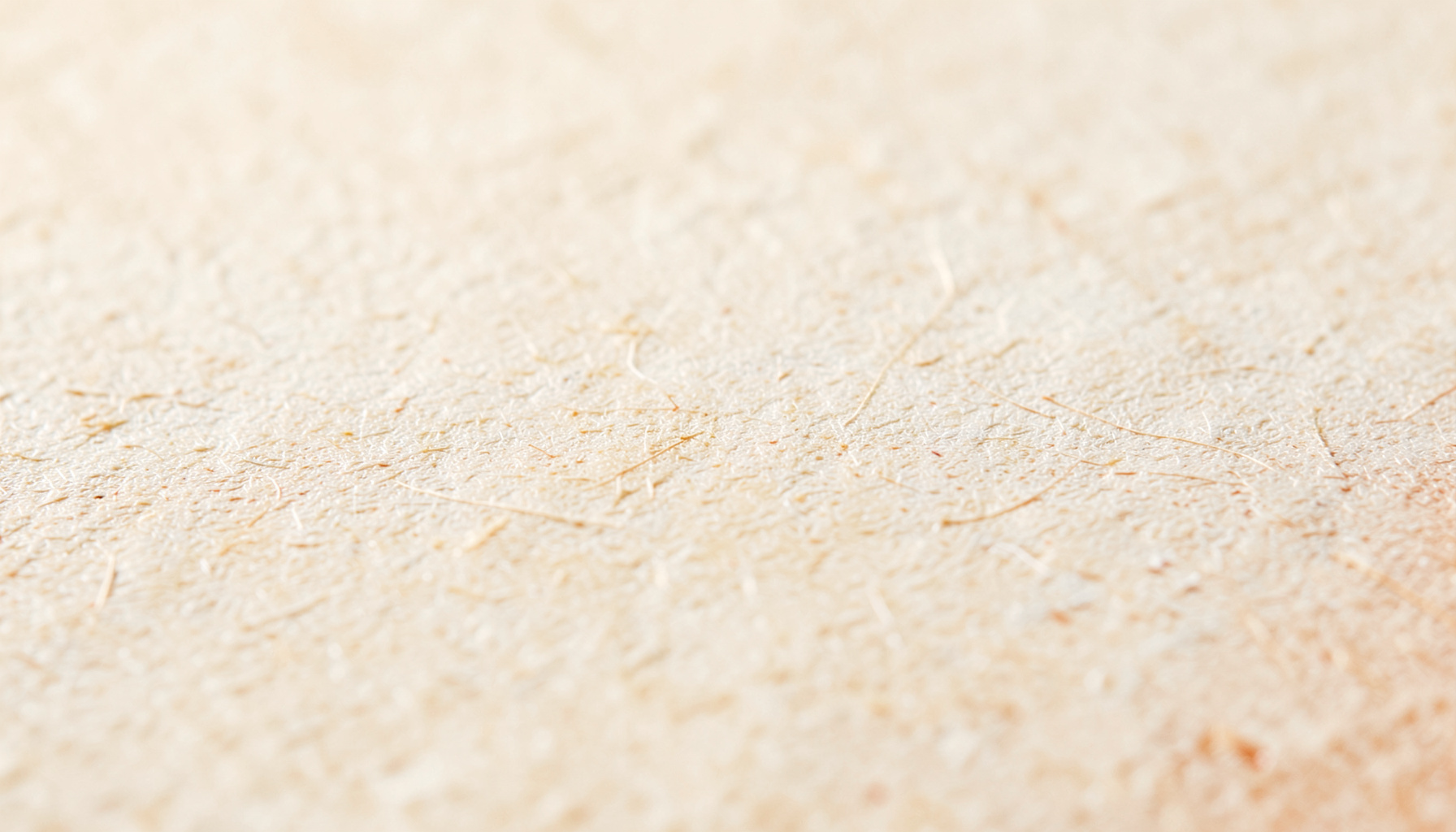 Warm textured paper surface in cream and beige tones with subtle fiber detail, evoking the tactile feel of a high-quality magazine page